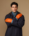 Men’s orange leather gloves with blue lining cuff, arms crossed