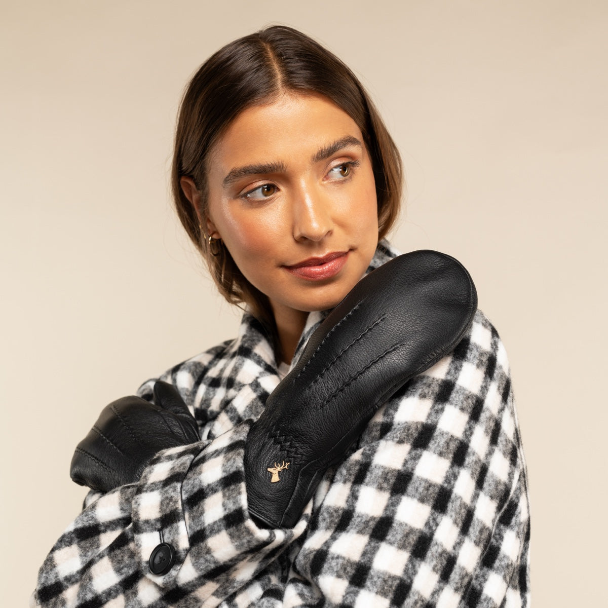 Black leather mittens with short faux fur cuff, stitched seams and deer logo.