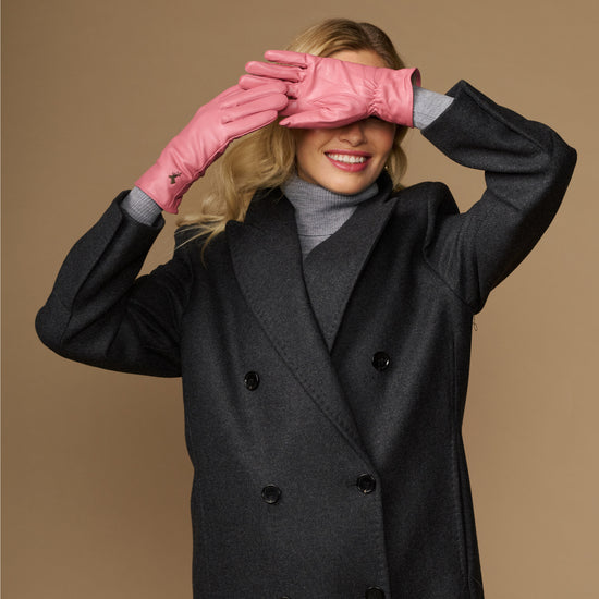 Women’s pink leather gloves covering eyes, with small logo on back of hand