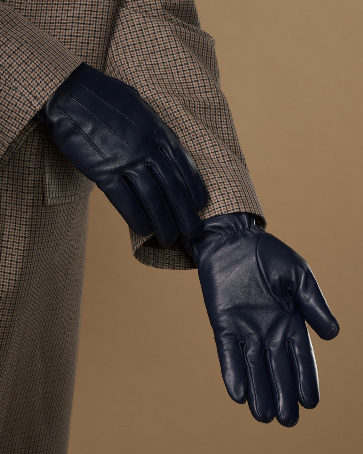 Single navy leather glove on extended hand, showing palm and finger seams