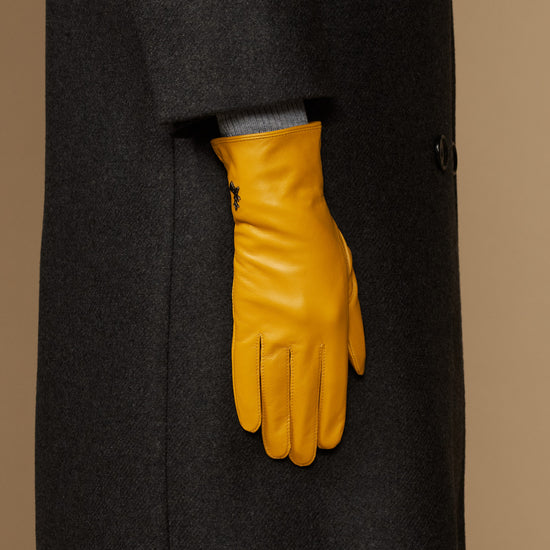 Single yellow leather glove with stitched finger seams and structured wrist cuff