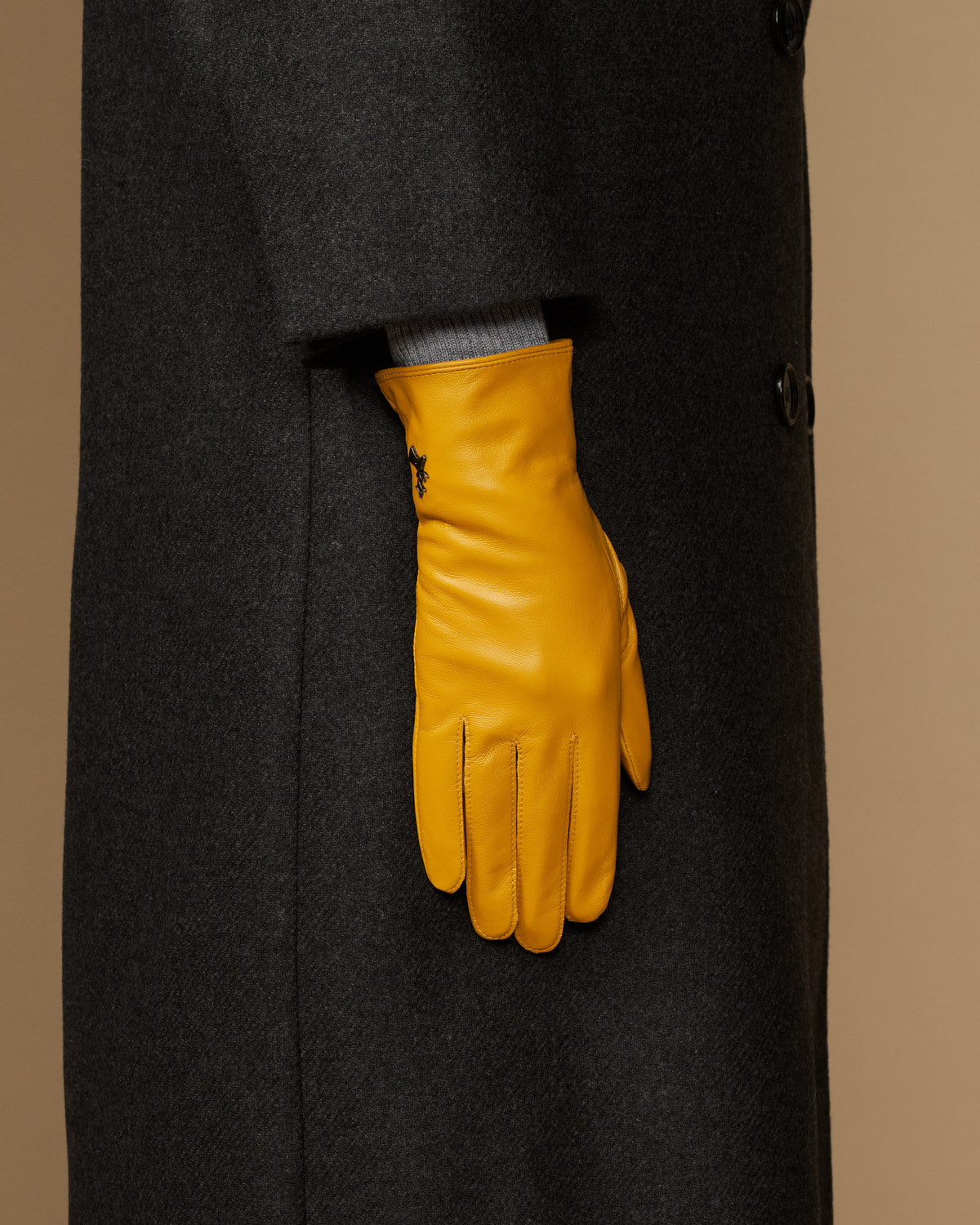Single yellow leather glove with stitched finger seams and structured wrist cuff
