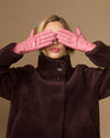 Pink leather gloves with dark sherpa lining, hands raised near face
