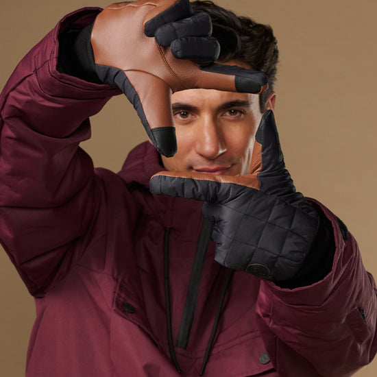 Men's insulated touchscreen gloves in dark gray, worn with hooded jacket