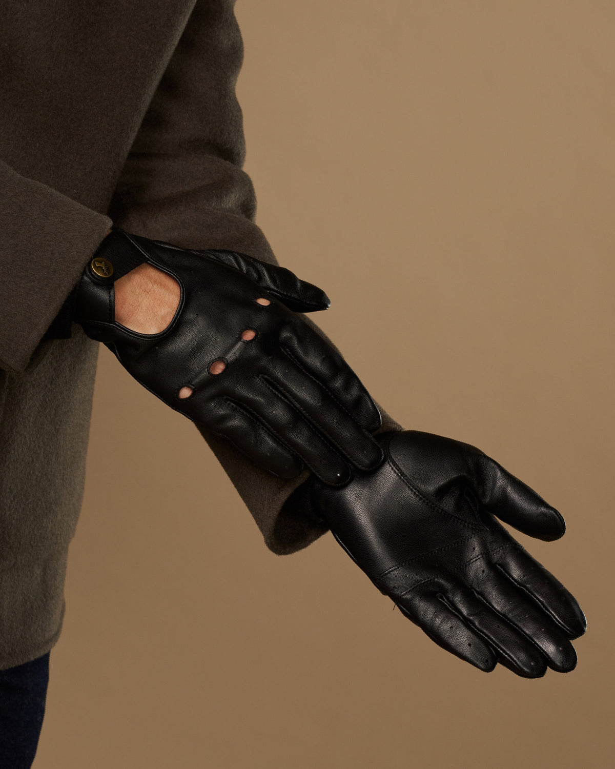 Black leather driving glove with touchscreen opening, worn with cuff and sleeve