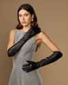 Women’s black leather elbow gloves, front pose with one arm across the chest