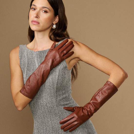 Cognac leather below-elbow gloves with smooth finish, worn with fingers forward