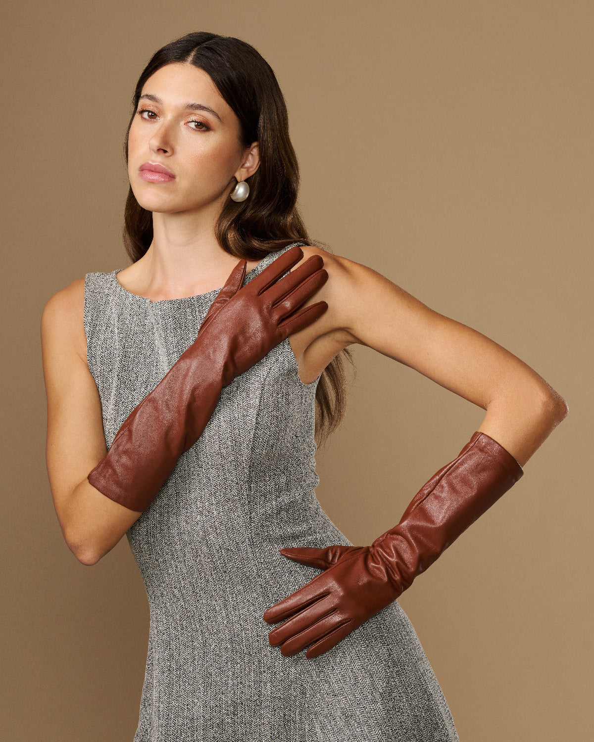 Cognac leather below-elbow gloves with smooth finish, worn with fingers forward