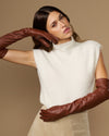 Chestnut brown leather opera gloves with long fingers, posed with arms reaching forward