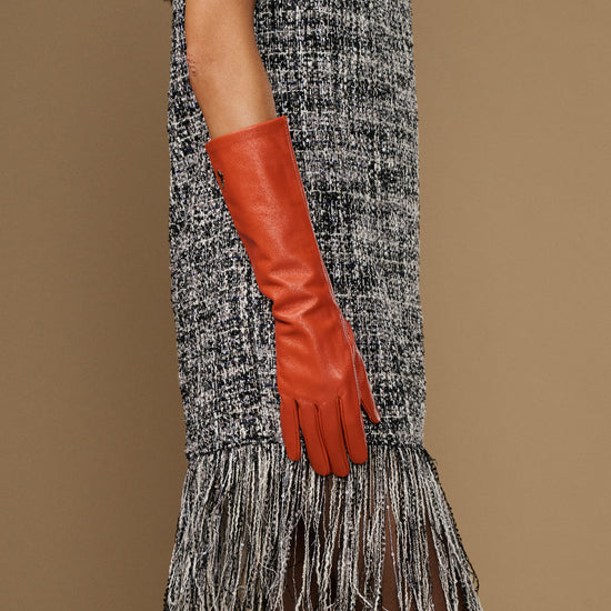 Women’s orange leather glove on raised arm, below-elbow length and tapered hand