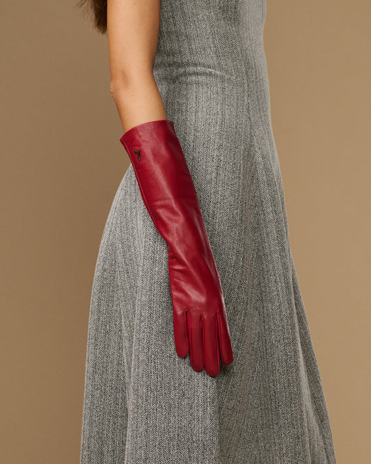 Red leather below-elbow glove on arm, showing long cuff and stitched fingertip seams