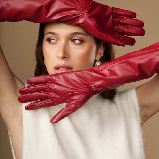 Red leather elbow gloves covering wrists, close-up on glove texture