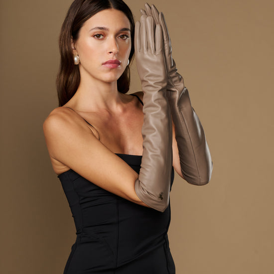 Taupe lambskin elbow-length leather gloves, model holding one glove up