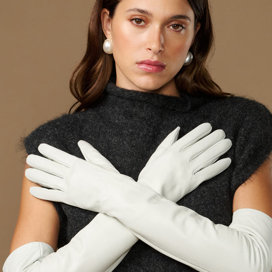 Women's white leather opera gloves with long fingers, hands crossed view