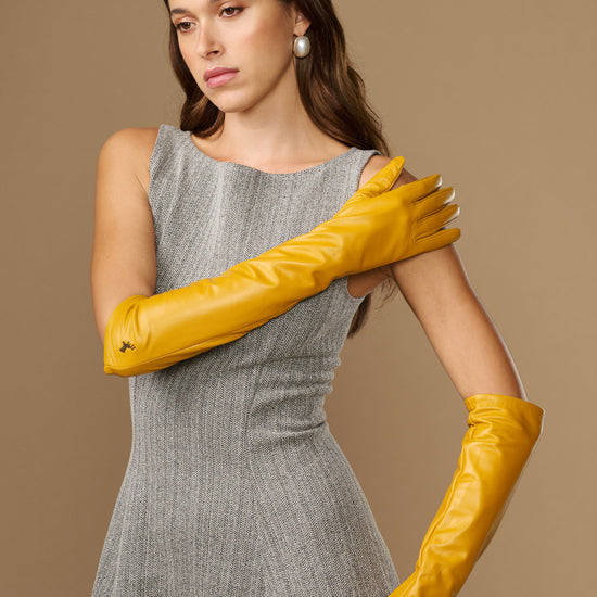 Yellow leather elbow gloves worn crossed at forearms