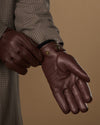 Brown leather glove close-up with press-stud wrist and finger stitching